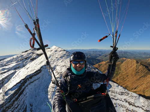 Paraglider pilot in awe as he flies over beautiful mountains  photo