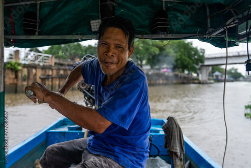 A tour guide steers a longtail boat on the Tapi River in Thailand photo
