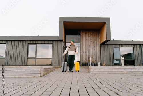Young traveler man with baggage in front of modern eco hotel photo