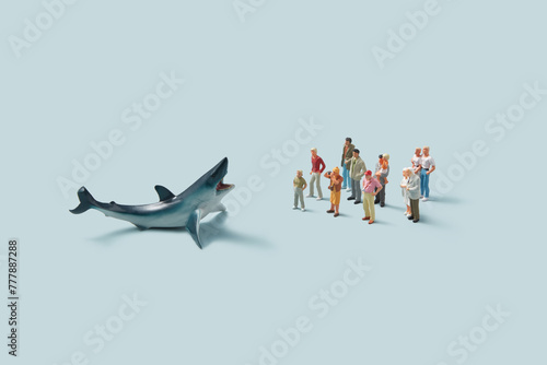 Miniature people figurines taking photos of terrifying big shark