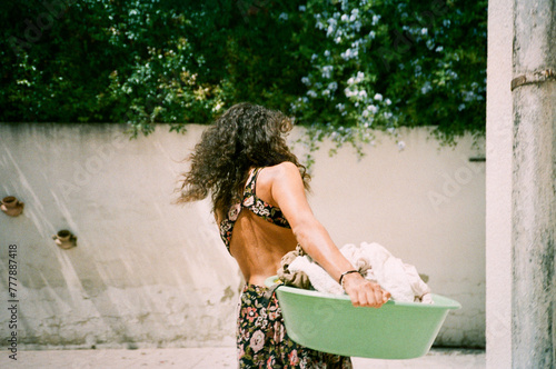 Curly hair woman carrying laundry basket on a sunny day