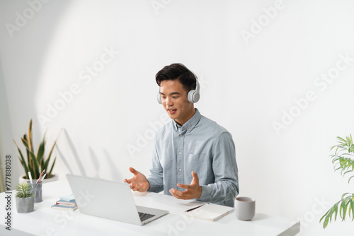  Smiling guy headset gesticulating with hands and watching laptop