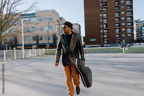 Man walking with guitar case in the city. photo