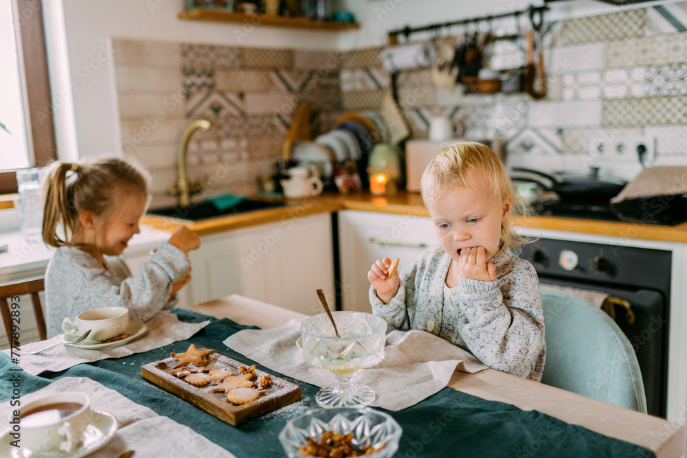 Two little funny sisters eating festive dinner together in the kitchen Two little funny sisters eating festive dinner together in the kitchen