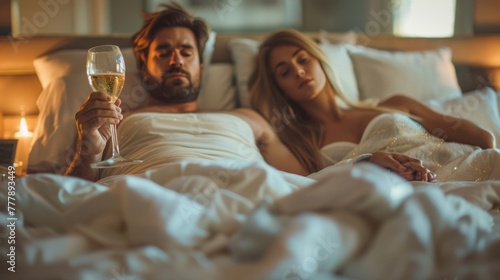 Man and woman lying in bed with champagne