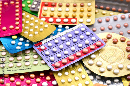 Oral contraceptive pill on pharmacy counter with colorful pills strips background.