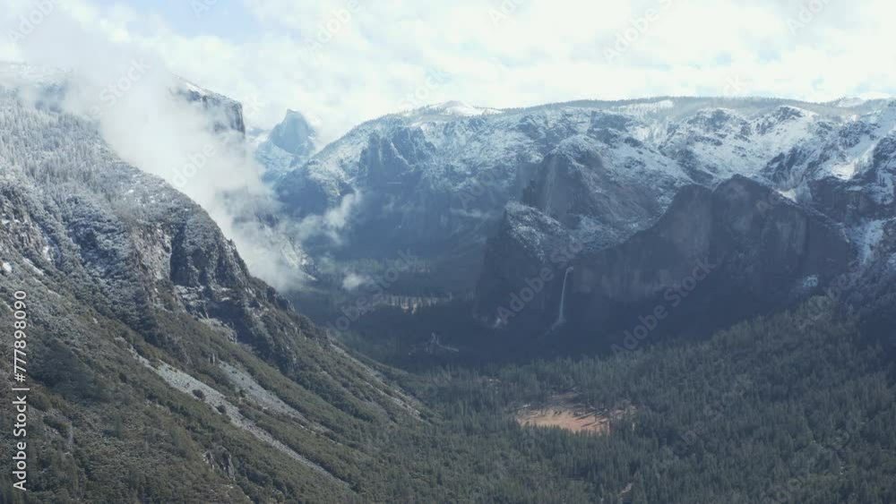 Aerial pan shot of Yosemite snow mountains, cliffs, valley, and waterfalls Aerial pan shot of Yosemite snow mountains, cliffs, valley, and waterfalls