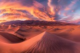 A panorama of a desert landscape at sunset, with rolling sand dunes casting long shadows and the sky ablaze with color