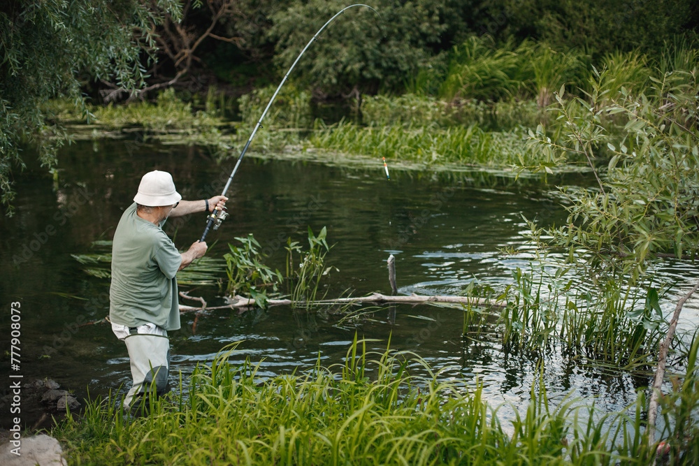 Fisherman with fishing rod near the lake at summer