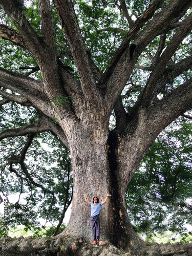 Woman standing on big roots of a giant tree to take shelter