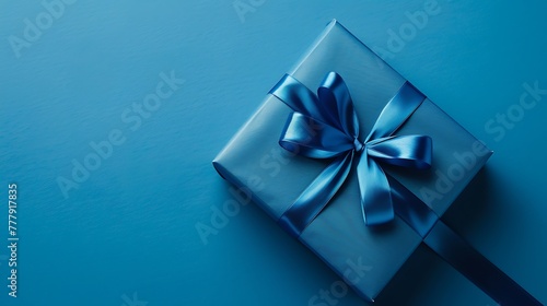 Blue gift box tied with blue ribbon is being unwrapped on blue background © Robert