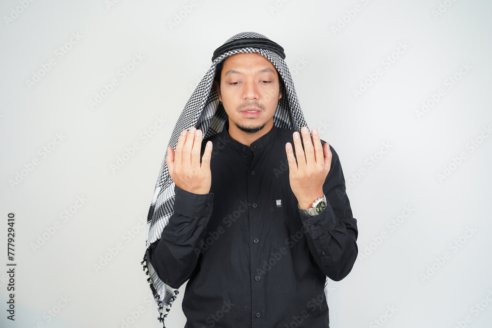 Asian muslim man is praying with hands up, wearing Arab turban sorban in copy space isolated Asian muslim man is praying with hands up, wearing Arab turban sorban in copy space isolated