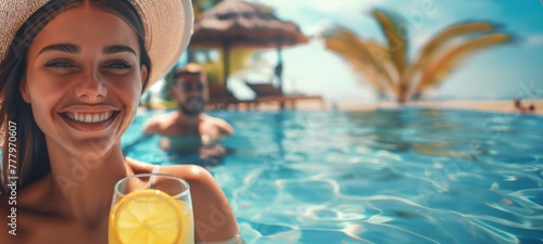 Joyful tanned woman in a hat with flowing hair and a cocktail smiles in the pool of a beautiful resort on a sunny day. Banner with copy space #777970607