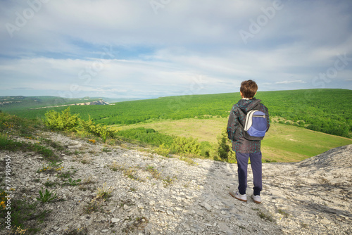 Boy standing and looking at mountainous landscape. © GIS