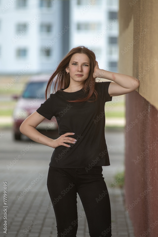 Portrait of a young beautiful long-haired girl outdoors in dark clothes.