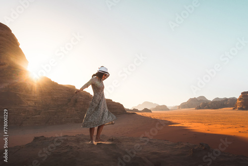 Happy joyful woman tourist stand and dance on cliff barefoot at viewpoint and enjoy holiday vacation in Wadi rum panorama on sunrise. Popular Wadi Rum desert in Jordan