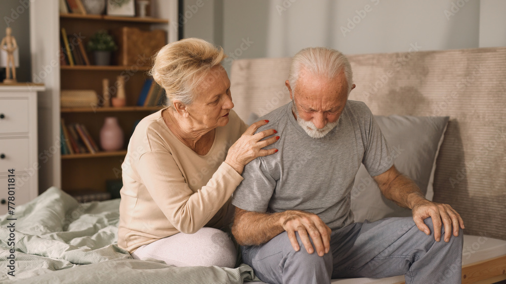 Elderly woman comforting her ill husband in bedroom