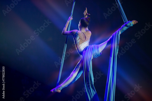 Performance by a circus acrobat artist. Girls perform aerial acrobatic elements on fabric.