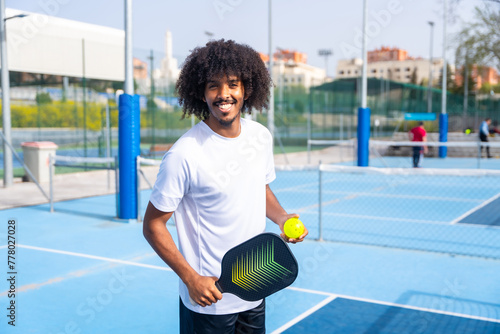 Man with afro hairstyle smiling in a pickleball court photo