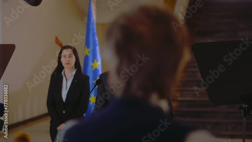 Senior EU representative answers press questions and gives interview for TV breaking news in parliament hall. Confident political speech during press conference. Campaign speech. Political discourse. photo