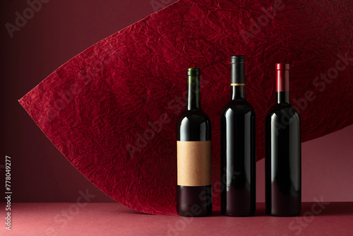 Bottles of red wine on a red background. © Igor Normann