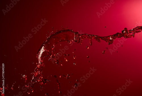 Red wine splash on a dark red background. © Igor Normann