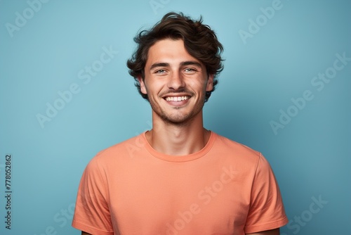 A man with a smile on his face is wearing an orange shirt