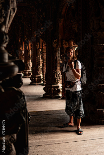 Man with long hair standing in a temple on a vacation, travel background image