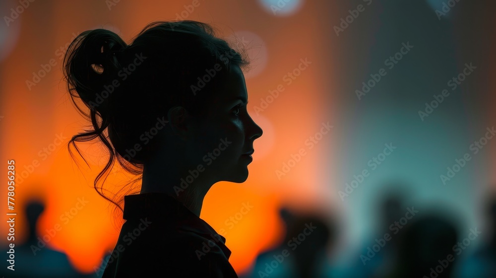 A woman with a bun on her head is looking at the camera. The image has a moody and mysterious feel to it, as the woman's face is the only thing visible. The background is blurry