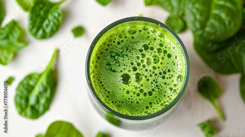 Freshly blended green juice in a glass surrounded by spinach leaves © Roman Korneev