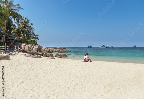 Tourist man sitting relax on the beach  at Koh Nang Yuan paradise island enjoy turquoise water sea with blue sky suratthani , thailand