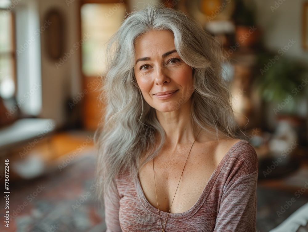 Obraz premium Beautiful mature senior woman at home in the living room smiling at the camera