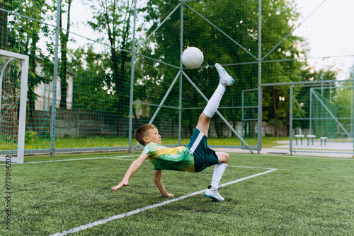 a boy, a football player, kicks the ball through himself. Kick on the soccer goal photo