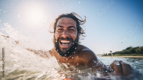A man surfer learns to catch waves. First steps in surfing sport. newcomer surfer catches a wave kneeling on a board with ecstatic expression photo