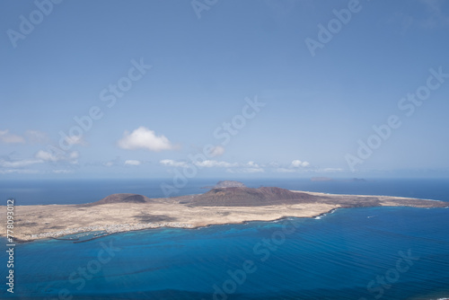 Island of La Graciosa from the viewpoint of El Rio. Turquoise ocean. Blue sky with big white clouds. Caleta de Sebo. Village. volcanoes. Lanzarote, Canary Islands, Spain © Jess