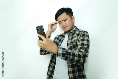 Young Asian man with a sad expression looking at smartphone photo