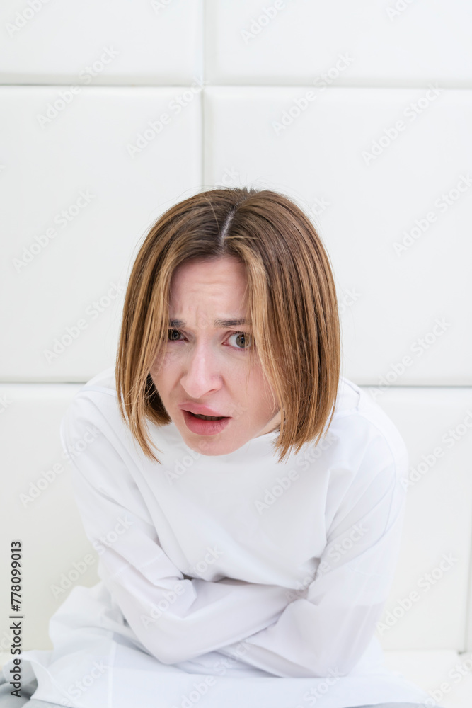 Young frustrated girl in a straitjacket is in an isolated white room in a mental hospital Young frustrated girl in a straitjacket is in an isolated white room in a mental hospital