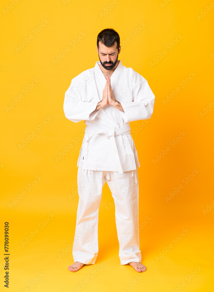Full-length shot of man over isolated yellow background doing karate and saluting Full-length shot of man over isolated yellow background doing karate and saluting