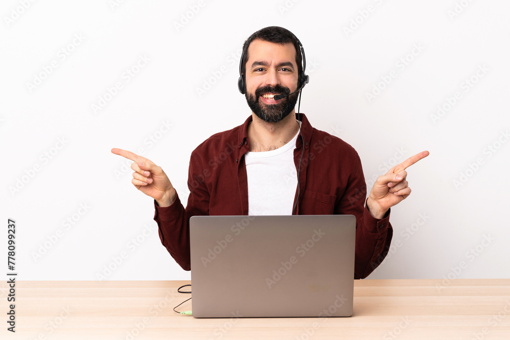 Telemarketer caucasian man working with a headset and with laptop pointing finger to the laterals and happy. Telemarketer caucasian man working with a headset and with laptop pointing finger to the laterals and happy.