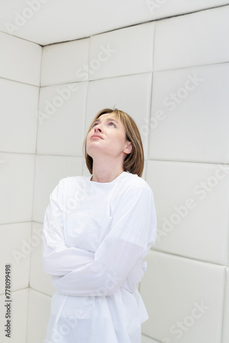 Young frustrated girl in a straitjacket is in an isolated white room in a mental hospital 