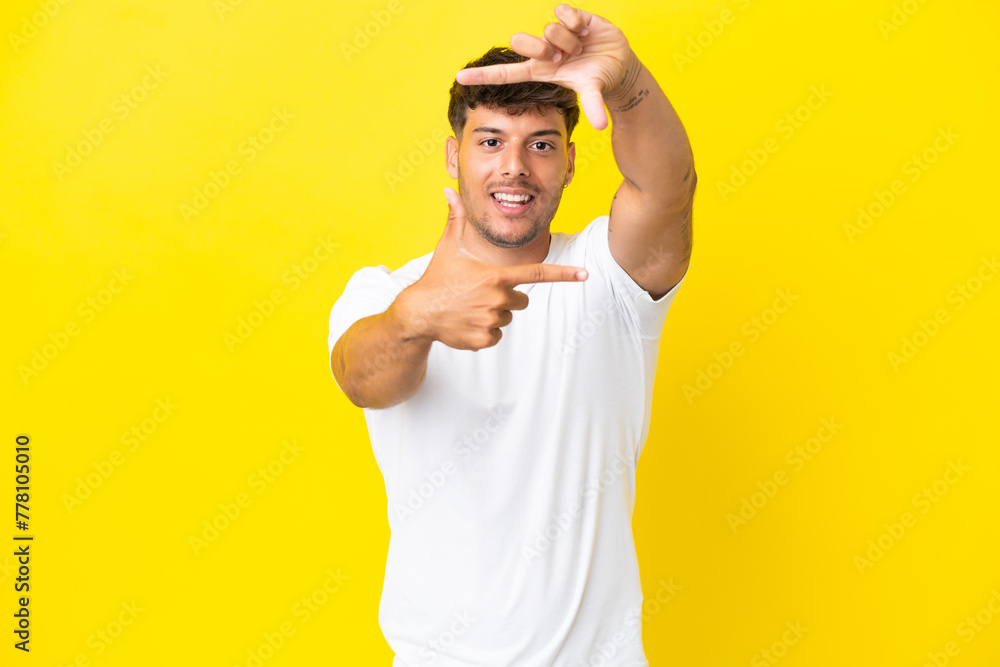Young caucasian handsome man isolated on yellow background focusing face. Framing symbol Young caucasian handsome man isolated on yellow background focusing face. Framing symbol