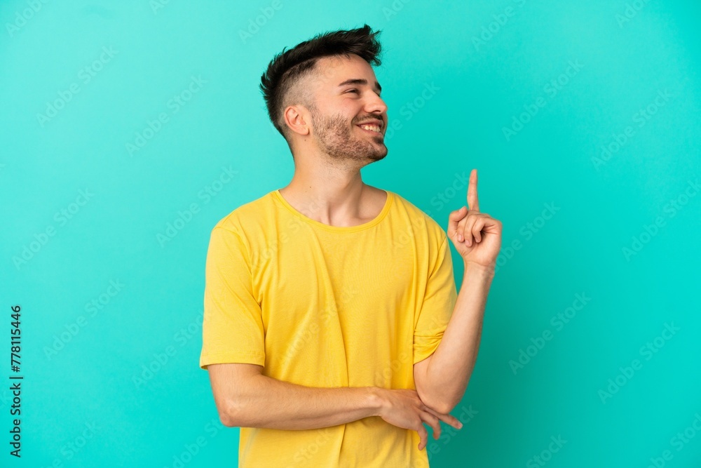 Young caucasian man isolated on blue background pointing up a great idea Young caucasian man isolated on blue background pointing up a great idea