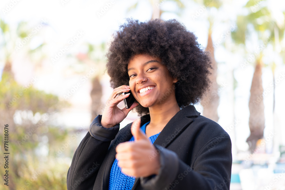 African American girl at outdoors keeping a conversation with the mobile while doing thumbs up African American girl at outdoors keeping a conversation with the mobile while doing thumbs up