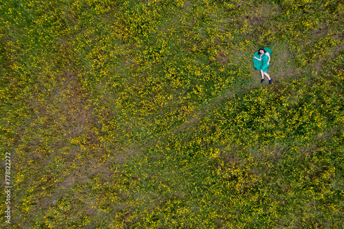 Overhead view of woman laying down on blooming meadow grass field. Spring time outdoor