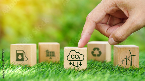 Billede på lærred CO2 emission reduction symbol target on wooden cube with hands in green natural background for Decreasing CO2 in environment concept ,carbon footprint, renewable energy business