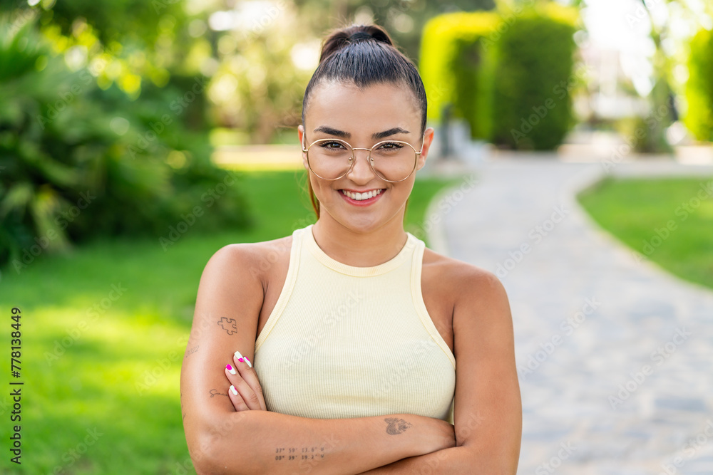 Young pretty woman with glasses at outdoors keeping the arms crossed in frontal position