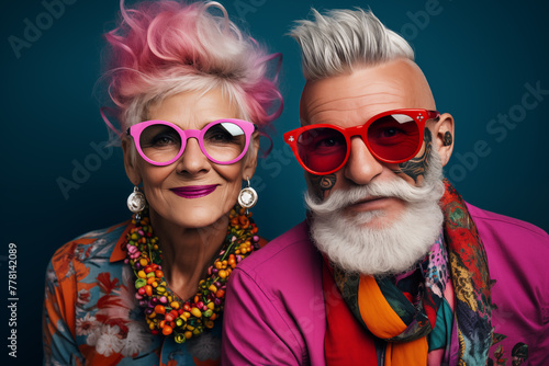 Extravagant senior couple portrait. Fashionable grandfather and grandmother wearing elegant clothes. Stylish cute old man and woman on colored background © Yelyzaveta