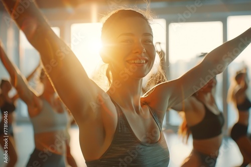 beautiful woman in sportswear enjoy dancing in fitness studio lit by natural light through windows in fitness class. blur group of happy fitness member dancing at background