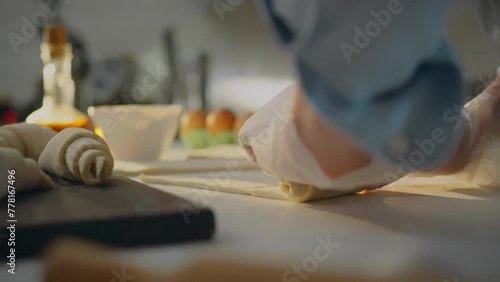 Bakery. A young chef dressed in comfortable work clothes prepares fresh croissants in an industrial bakery. Mature man preparing fresh baked goods adheres to the traditions of preparing breakfast photo