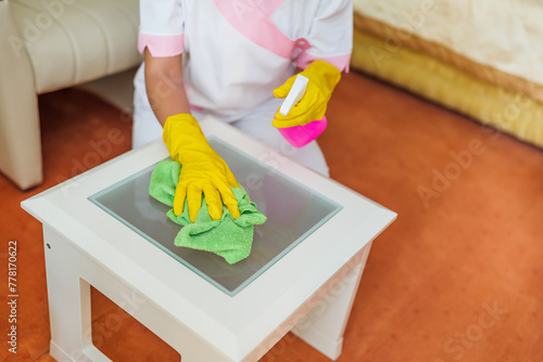 Close up image of hotel maid cleaning table in a room.	